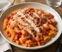 Rigatoni i cremet tomatsauce med grillet kylling, sprød bacon og revet parmesan